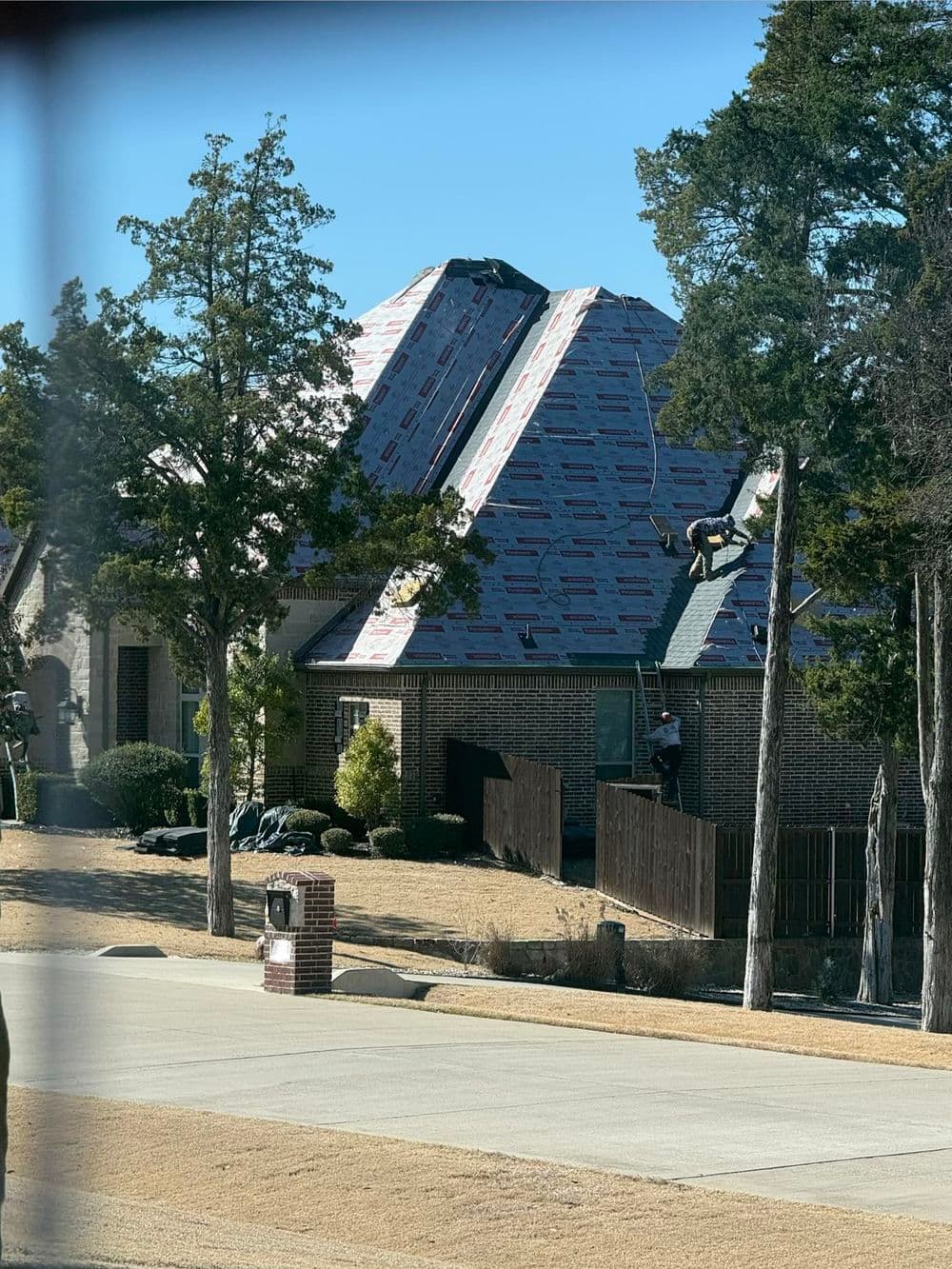 Roofing project in progress on a residential home with workers and materials on site.